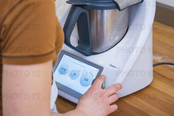 Person operating the display of a modern food processor, Vegan Tart Production, Haselstaller Hof, Gechingen, Germany