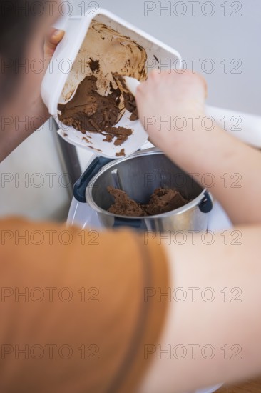 Person scrapes chocolate mix into a food processor, vegan cake production, Haselstaller Hof, Gechingen, Germany