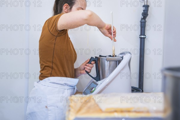 Woman mixes ingredients in a mixer in the kitchen, vegan cake production, Haselstaller Hof, Gechingen, Germany