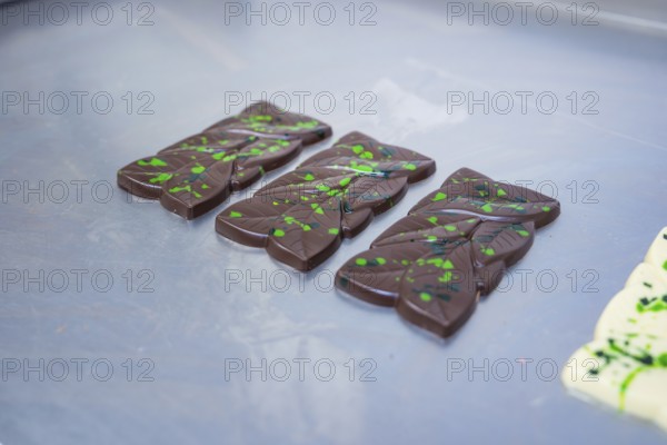 Three dark chocolate bars with green patterns on a table, vegan chocolate production, Haselstaller Hof, Gechingen, Germany