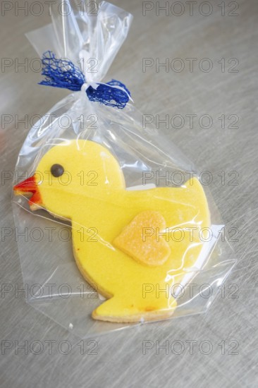 Yellow duck cookie with orange beak, wrapped in transparent film with blue ribbon, Easter production of regional products, Haselstaller Hof, Gechingen, Calw district, Germany