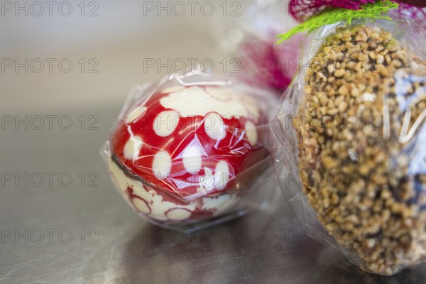 Chocolate Easter egg with nuts and a red and white egg, both packed in plastic, Easter production of regional products, Haselstaller Hof, Gechingen, Calw district, Germany