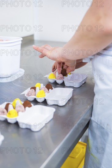 A person wraps chocolates in a package in a kitchen, chocolate quail eggs, Easter production, Haselstaller Hof, Gechingen, Germany