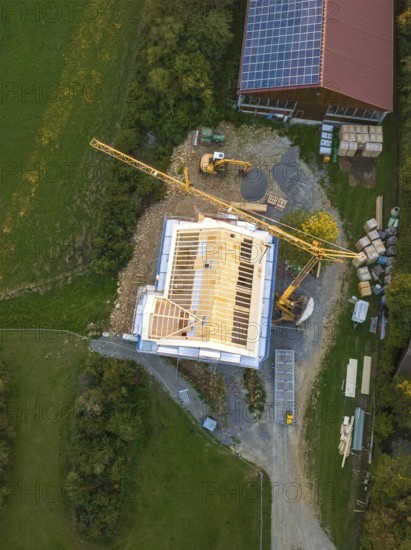 Construction site with crane and solar panel on a large building from a bird's eye view, timber house construction, Gechingen, Germany