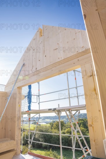 Timber building under construction with scaffolding and views of the landscape under blue sky, timber house construction, Gechingen, Germany