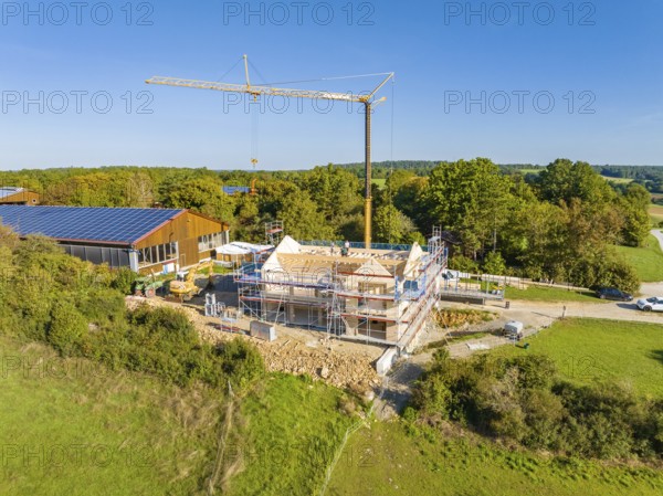 A construction site with a crane and a house under construction, surrounded by green nature and scaffolding, timber house construction, Gechingen, Germany