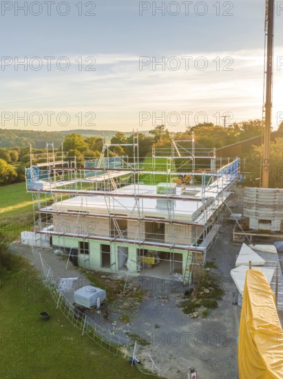 Building in nature with scaffolding and crane at sunset, timber house construction, Gechingen, Germany