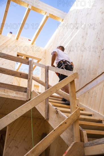 Workers climbing a wooden staircase in a partially converted building, timber house construction, Gechingen, Germany