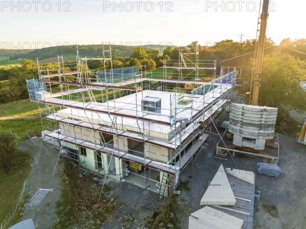 Building under construction with scaffolding in a rural area at sunset, timber house construction, Gechingen, Germany