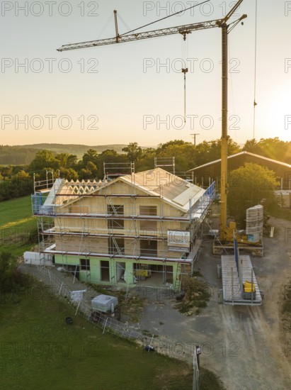 House construction with a crane and scaffolding in a rural area at sunset, timber house construction, Gechingen, Germany