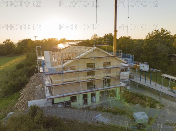 Building under construction at sunset, surrounded by scaffolding in a rural area, timber house construction, Gechingen, Germany
