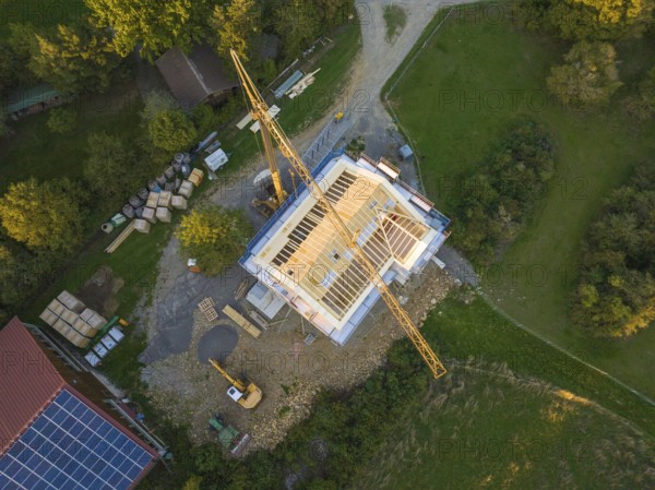 Bird's eye view of a construction site with crane and semi-finished building in a green area, Holzhausbau, Gechingen, Germany