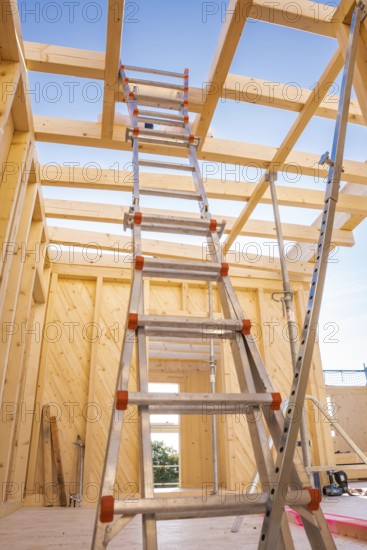 Interior view of a timber structure under construction, ladder leading upwards under blue sky, timber house construction, Gechingen, Germany