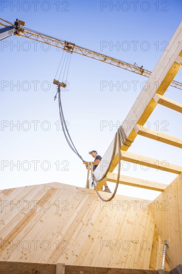 Timber structure under construction with a crane and a blue sky in the background, timber house construction, Gechingen, Germany