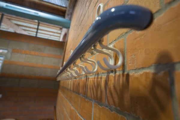 White coat hooks on a brick wall from a close perspective, Schlehengäu Sporthalle Gechingen, Calw district, Germany