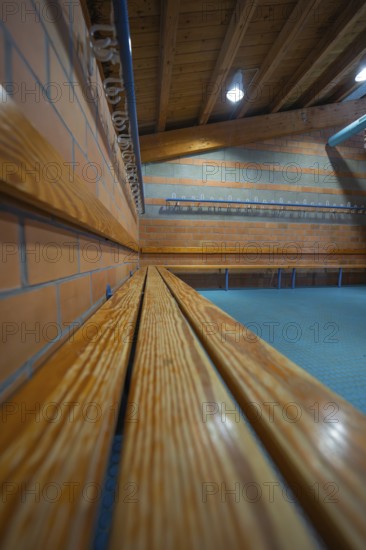 Long wooden bench on a brick wall with ceiling lights, Schlehengäu Sporthalle Gechingen, Calw District, Germany