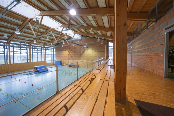 Interior view of a gym with wooden benches and large windows, Schlehengäu Sporthalle Gechingen, Calw district, Germany