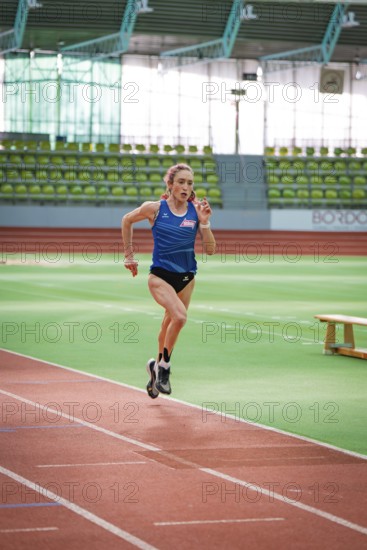 Woman running on a track in a stadium wearing a blue jersey, middle distance runner Katharina Jaiser, Sindelfingen Glass Palace, Germany