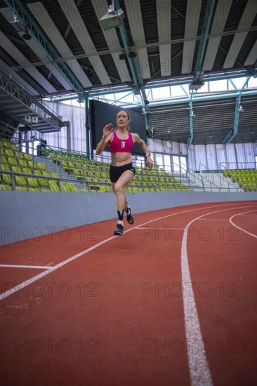 Female athlete sprints energetically on a red track in a sports complex, middle distance runner Katharina Jaiser, Sindelfingen Glass Palace, Germany