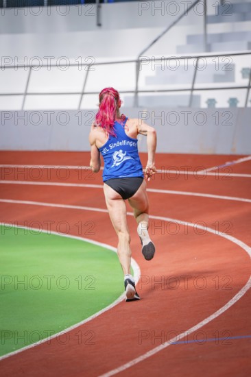 A sporty woman with pink hair dynamically runs along the curve in the stadium, middle distance runner Katharina Jaiser, Glaspalast Sindelfingen, Germany