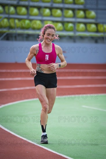 Determined, smiling woman running on an indoor track with visible enthusiasm, middle distance runner Katharina Jaiser, Sindelfingen Glass Palace, Germany