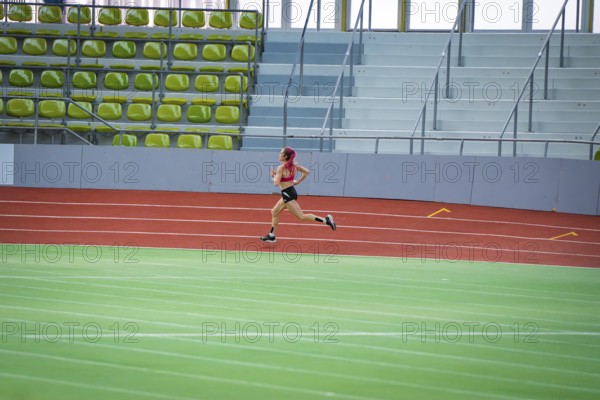 Woman running resolutely on a red indoor track, middle distance runner Katharina Jaiser, Sindelfingen Glass Palace, Germany