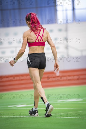 Female athlete in sports hall on synthetic track in dynamic posture, middle distance runner Katharina Jaiser, Sindelfingen Glass Palace, Germany
