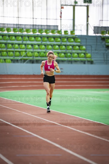 Sporty dressed woman running on an indoor track, showing speed and focus, middle distance runner Katharina Jaiser, Sindelfingen Glass Palace, Germany