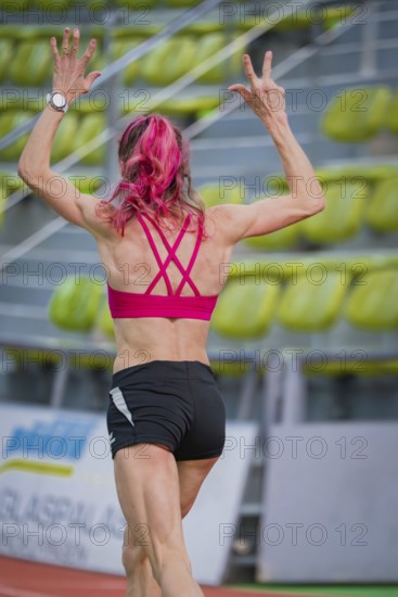 Sportswoman raises her arms while running on a track in a hall, middle distance runner Katharina Jaiser, Sindelfingen Glass Palace, Germany