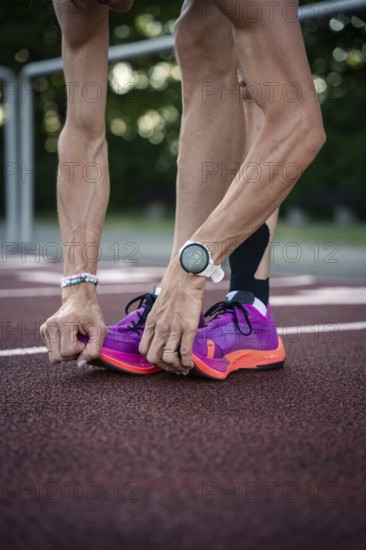 Close-up of person lacing pink running shoes on track with wristwatch, middle distance runner Katharina Jaiser, Gechingen, Germany