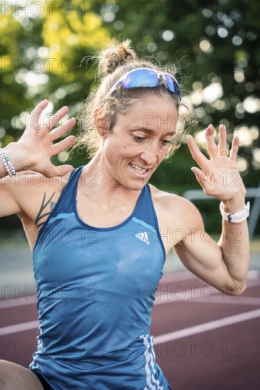 A happy runner in a blue sports outfit raises her hands with joy on the track, middle distance runner Katharina Jaiser, Gechingen, Germany