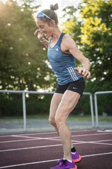 Woman dancing enthusiastically on a running track in summer sunlight, middle distance runner Katharina Jaiser, Gechingen, Germany