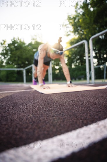 A woman in plank position on a running track at sunset, middle distance runner Katharina Jaiser, Gechingen, Germany