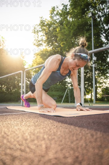 Woman doing yoga exercises on a mat in sunlight, showing concentration and commitment, middle distance runner Katharina Jaiser, Gechingen, Germany