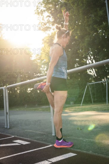 Woman standing on a running track while stretching, raised in sunlight, middle distance runner Katharina Jaiser, Gechingen, Germany