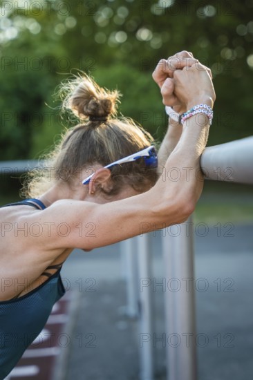 Female athlete in warm-up leaning against a barrier. Focused and concentrated atmosphere, middle distance runner Katharina Jaiser, Gechingen, Germany