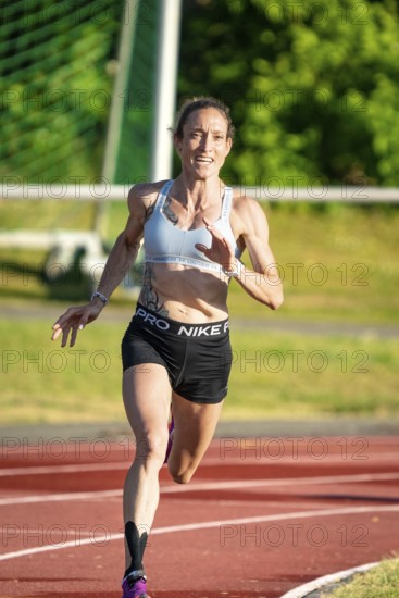 Woman running with energy on a sports track in green surroundings, middle distance runner Katharina Jaiser, Gechingen, Germany