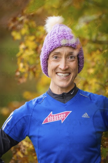 Woman wearing purple hat and blue sweater smiling in autumn surroundings, middle distance runner Katharina Jaiser, Gechingen, Germany