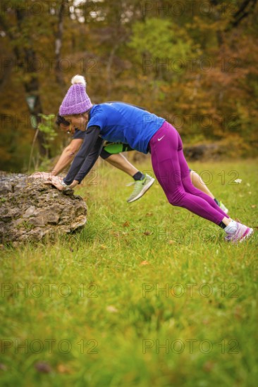 Two people doing outdoor sports exercises on rocks in autumn terrain, middle distance runner Katharina Jaiser, Gechingen, Germany
