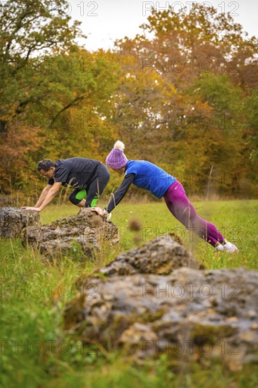 Two people training over rocks in an autumnal landscape, middle distance runner Katharina Jaiser, Gechingen, Germany