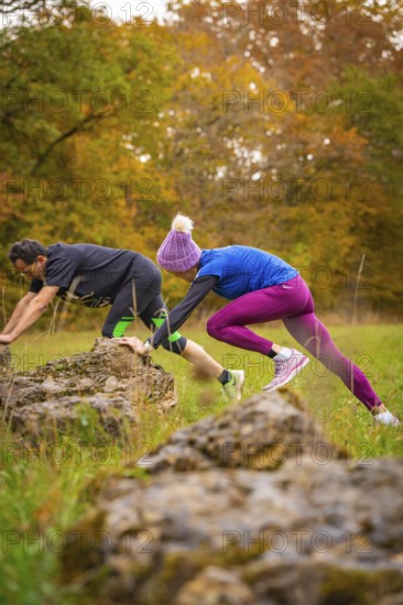 Man and woman training over rocks in an autumn park, middle distance runner Katharina Jaiser, Gechingen, Germany