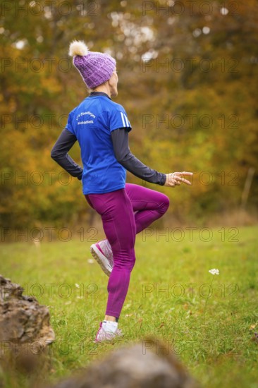 Woman wearing pink sports pants and blue jacket training in autumn forest, middle distance runner Katharina Jaiser, Gechingen, Germany