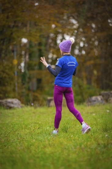 Woman in sporty clothes running in the forest surrounded by autumn trees, middle distance runner Katharina Jaiser, Gechingen, Germany