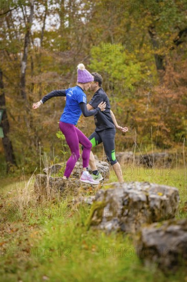 Two people train in the forest on rocks in an autumnal atmosphere, middle distance runner Katharina Jaiser, Gechingen, Germany