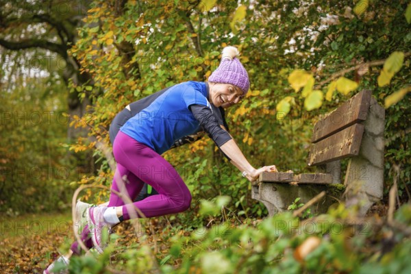 Woman stretching on a bench in an autumnal park, middle distance runner Katharina Jaiser, Gechingen, Germany
