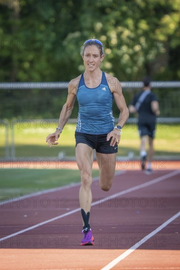 Athlete runs purposefully on the track in green, sunny surroundings, middle distance runner Katharina Jaiser, Gechingen, Germany