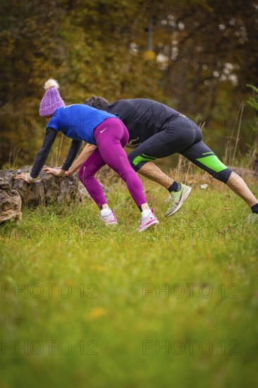 Two athletes doing exercises on rocks in an autumnal forest environment, middle distance runner Katharina Jaiser, Gechingen, Germany