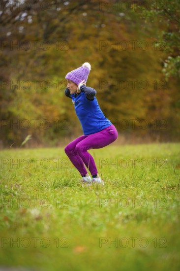 Woman wearing colorful sportswear doing jumping exercises on an autumnal meadow, middle distance runner Katharina Jaiser, Gechingen, Germany