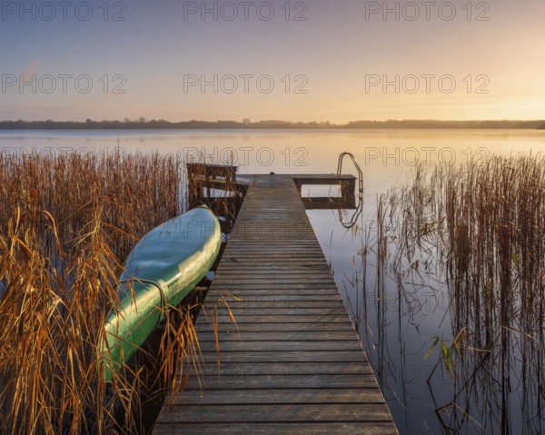 Jetty and inverted boat at Schaalsee in the first morning light, reeds in autumn colors, Schaalsee Biosphere Reserve, Mecklenburg-Western Pomerania Germany