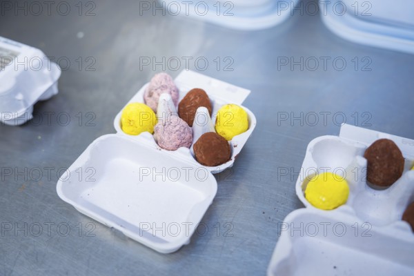 Different colored chocolate eggs in an egg carton on a metal surface, chocolate quail eggs, Easter production, Haselstaller Hof, Gechingen, Germany
